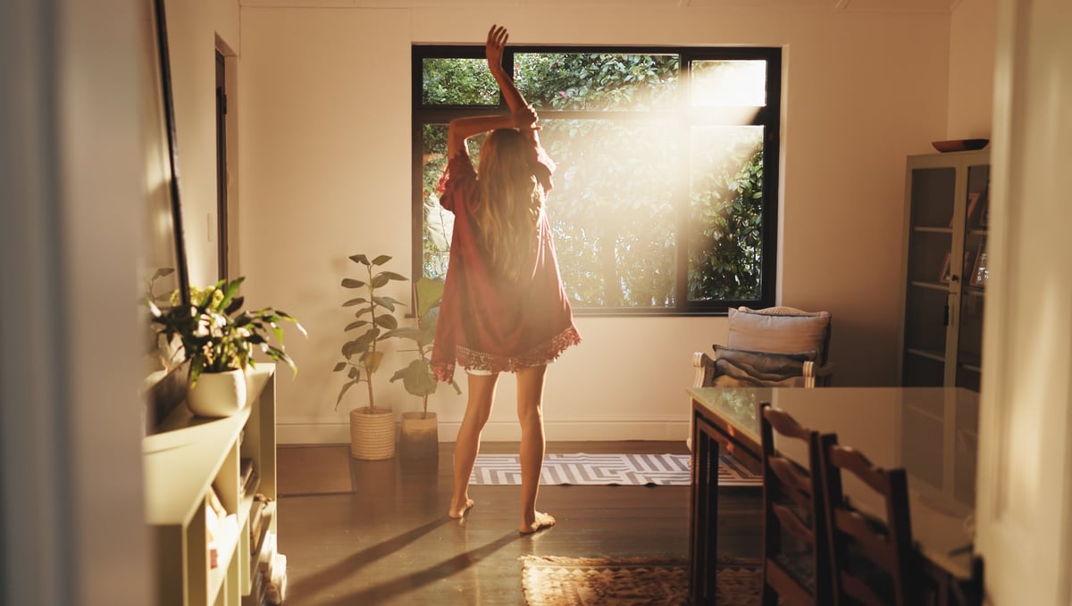 A woman stretching by a bright window in the morning, ready to start a fresh new day