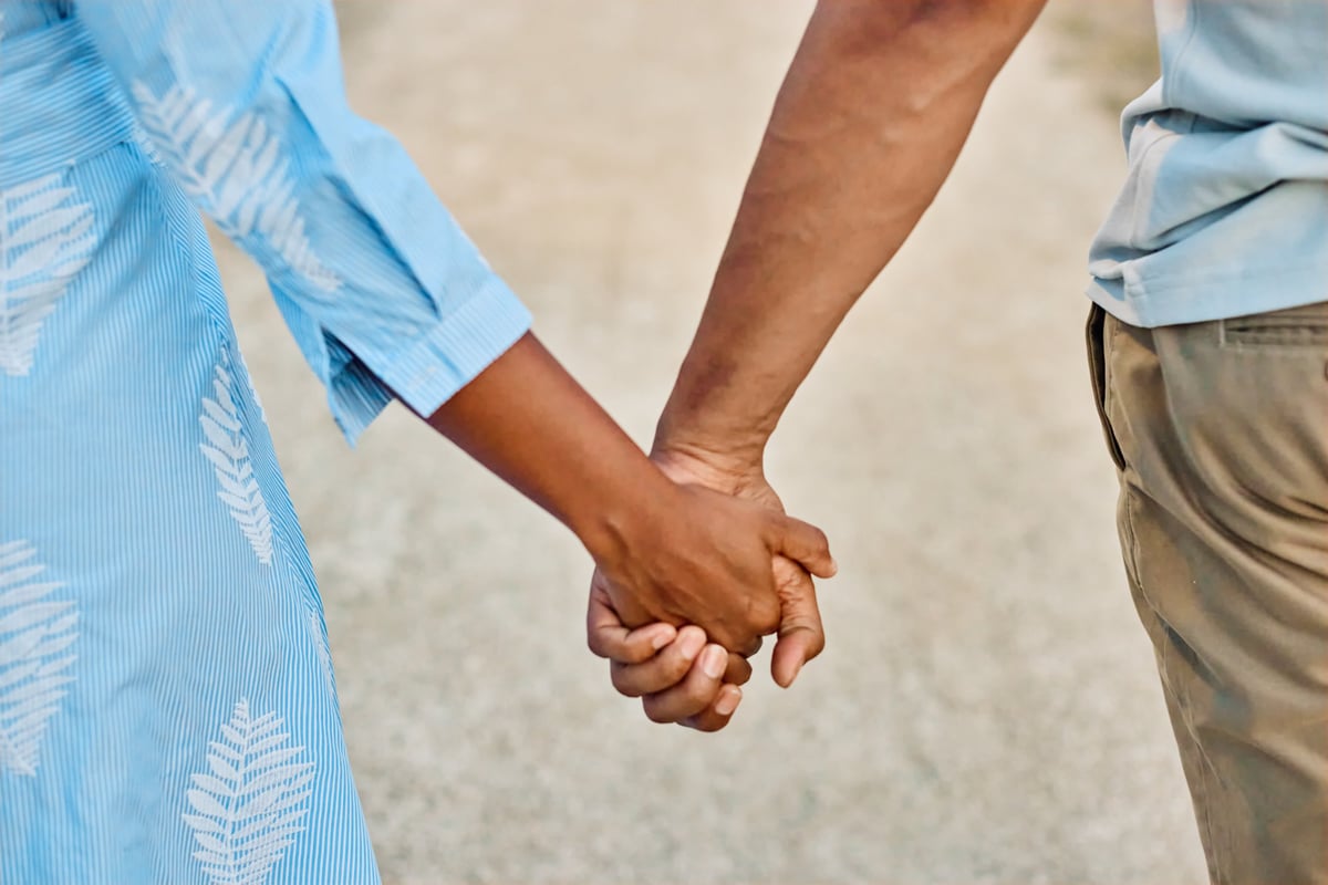 A couple walking together through a park, holding hands