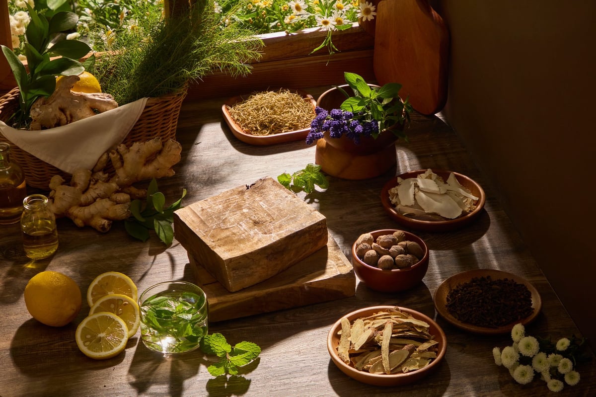 Herbs, roots, and wooden bowls arranged naturally in warm sunlight on a wooden surface
