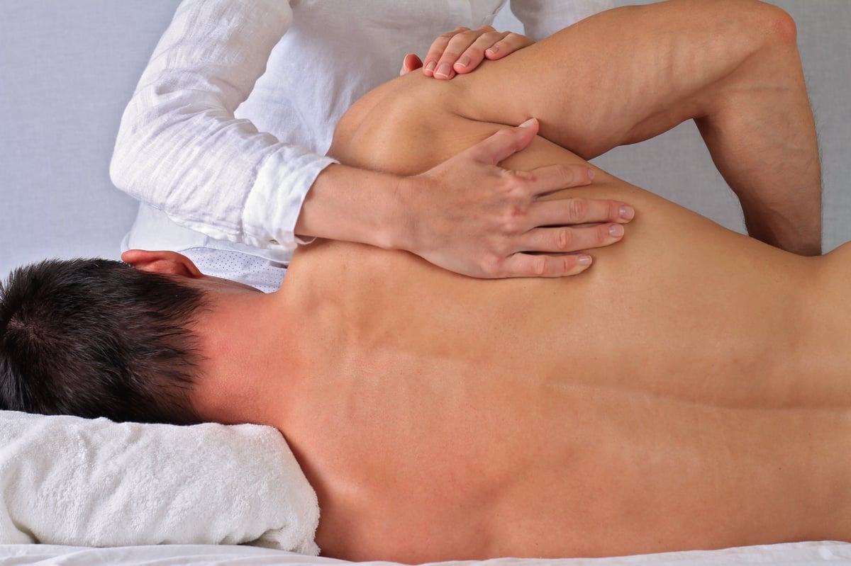 Therapist performing gentle hands-on manual therapy treatment on patient's back