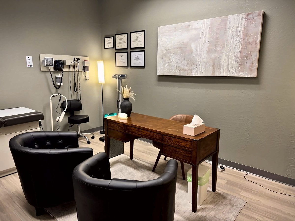 Naturopathic consultation room with a wooden desk, leather tub chairs and abstract artwork