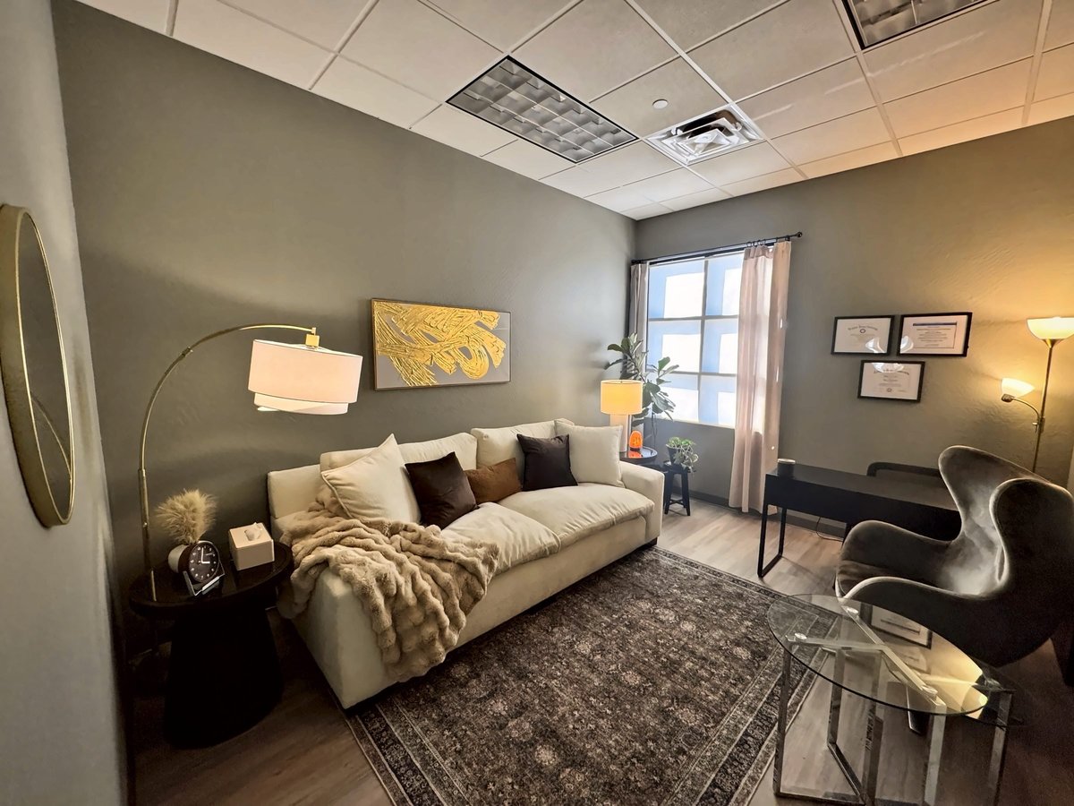 Therapy office with a cream sofa, faux fur throw, brass arc lamp and gold abstract art